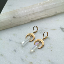 Load image into Gallery viewer, A white iridescent crystal hangs on gold crescent moon earring settings.