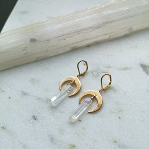 A white iridescent crystal hangs on gold crescent moon earring settings.